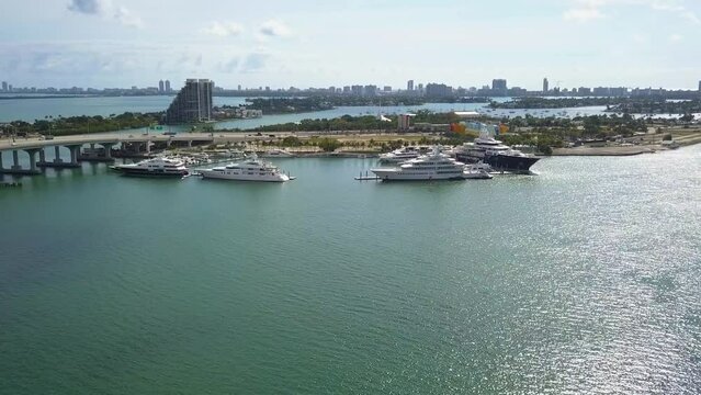 Aerial view towards big, expensive yachts, in sunny Island Gardens, Miami, USA - approaching, drone shot