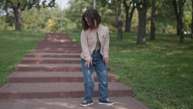 Wide shot confident positive little person with dwarfism dancing in slow motion in spring summer park. Happy carefree Caucasian young woman having fun enjoying leisure outdoors on weekend