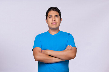 Latino young man arms crossed blue shirt white background