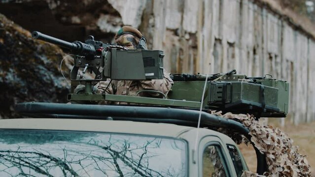 Professional military car with a firearm on its roof. A soldier in camouflage aiming at a target. High quality 4k footage
