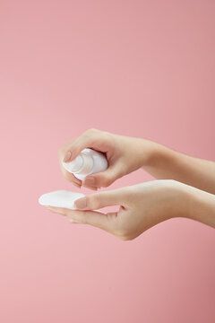 Topview of hand model using makeup remover on cotton pad in pink background for cosmetic advertising	
