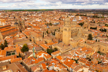 Fototapeta na wymiar Picturesque architecture of ancient central district of Salamanca with impressive gothic cathedral, baroque domes of Clerecia and Palace de Anaya and terracotta tiled roofs of houses in spring, Spain