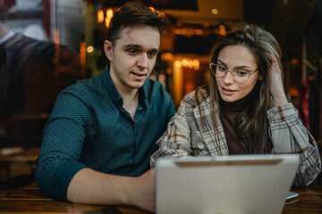 Two people young adult couple woman and man boyfriend and girlfriend or wife and husband sitting at cafe relationship concept use digital tablet for online search or video call real people copy space
