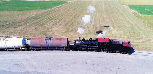 Aerial View of an Antique Steam Engine Doing Switching Dues at a Freight Yard in the Middle of Farmlands on a Sunny Day