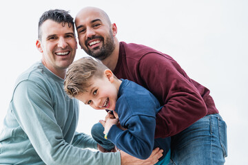 Gay fathers and son having fun together outdoor - LGBT diversity family love concept - Focus on left man face