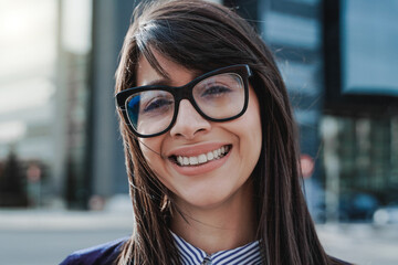 Young business woman working outside with office buildings on background - Focus on face