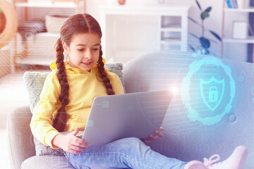 Cute little girl with laptop sitting on sofa at home. Concept of online safety and parental control