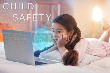 Cute little girl with laptop lying on bed. Concept of online safety