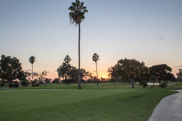 View of golf course with sun setting on the background