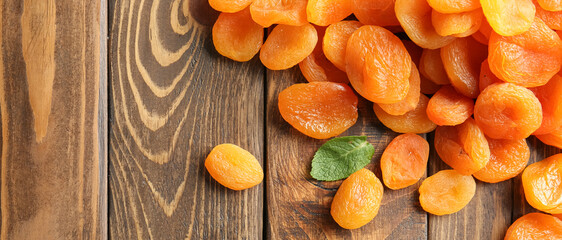 Tasty dry apricots on wooden background with space for text