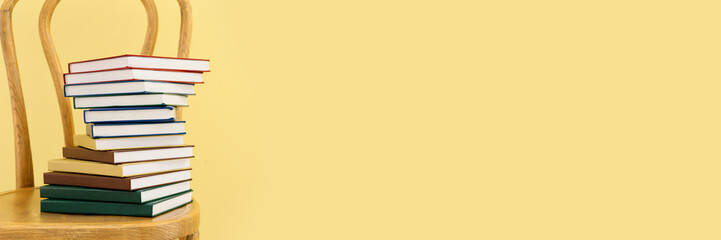 Many books on chair against yellow background. Banner for design