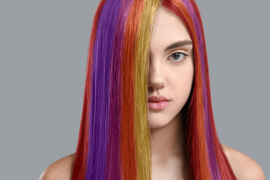 Young woman with beautiful colorful hair on grey background
