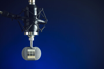 Stand with microphone on blue background, closeup