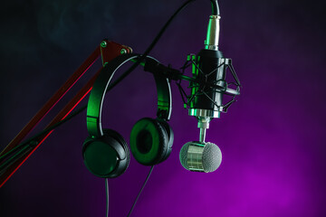 Stand with microphone and headphones on dark color background, closeup