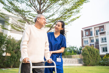 Asian young caregiver nurse support senior older male walking outdoors