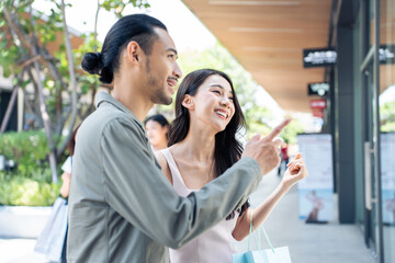 Asian young man and woman shopping goods outdoors in department store.	