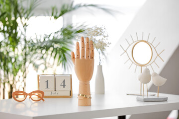Wooden hand with golden bracelet on table in room