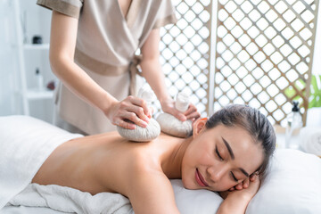 Obraz na płótnie Canvas Asian beautiful woman enjoy thai hot compress massage with herbal bags