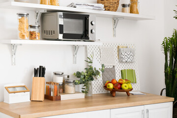 Counter with fruits and shelves with utensils in kitchen
