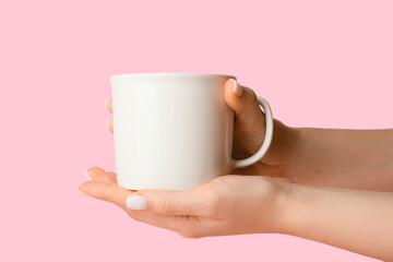 Woman holding ceramic cup on pink background, closeup