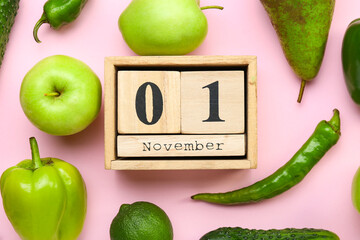 Fresh fruits, vegetables and wooden cube calendar with date NOVEMBER 1 on color background. World Vegan Day concept