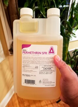 Wilmington, Delaware, U.S - May 14, 2022 - Holding a bottle of Permethrin SFR, a pesticide used to kill pests on plants