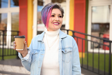 Beautiful woman with dyed hair and cup of coffee outdoors