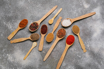 Spoons with aromatic spices on grey background