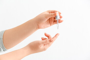 Woman applying serum onto hand on white background, closeup
