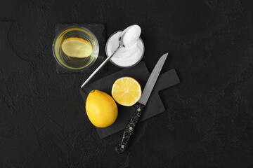 Bowl with baking soda, glass of water and lemons on dark background
