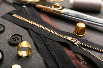 Set of stylish zippers and sewing supplies on dark background