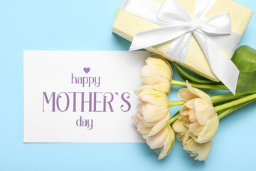 Card with text HAPPY MOTHER'S DAY, flowers and gift box on blue background, closeup