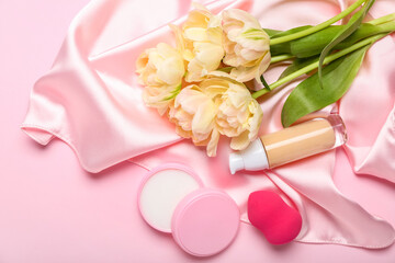 Bouquet of tulips, decorative cosmetics and makeup sponge on pink background