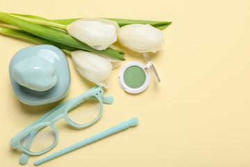 Beautiful white tulips, female accessories and decorative cosmetics on yellow background