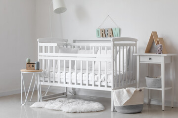 Fototapeta na wymiar Interior of light nursery with baby crib, lamp and tables