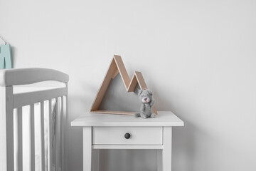 Table with toy and decor near light wall in nursery