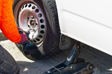 Mechanic changing car tire with tool. road help, changing and repairing tire, wheel. replacing tire at home, season.