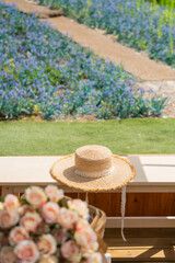 Flower in the picnis basket with summer hat with blue spring summer flowers blooming at the garden