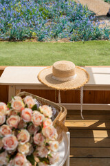 Flower in the picnis basket with summer hat with blue spring summer flowers blooming at the garden