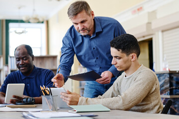 Mature Caucasian man working as English language teacher for immigrants explaining grammar rule to...