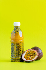 Passion fruit juice bottle and ripe passion fruit on green background, space for text. Tropical fruit juice bottle.