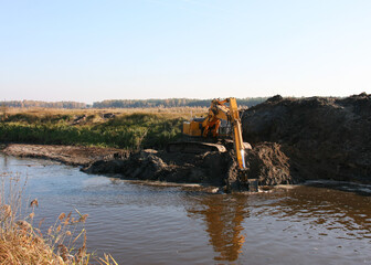 Excavator cleans the pond