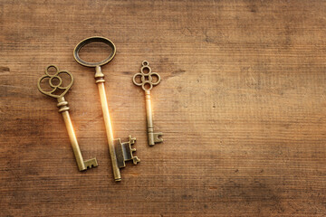 Top view image of old keys with golden light over wooden background
