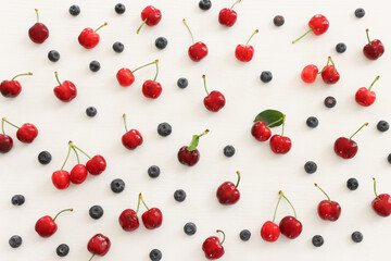 Naklejka na ściany i meble Top view image of colorful assorted mix of berries, blueberry and sweet cherry over wooden white background