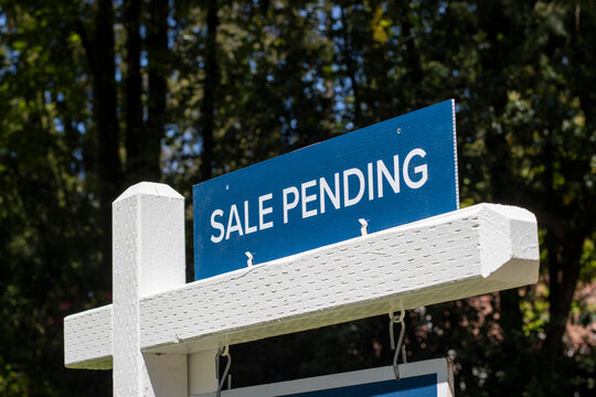 Closeup of a "Sale Pending" real estate sign outside a residential single-family house on the market. Pandemic housing market frenzy concept.