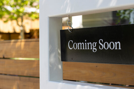 Closeup of a "Coming Soon" real estate sign outside a residential single-family house. Housing market inventory concept.