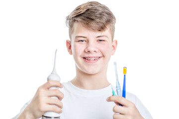 Orthodontic treatment. Dental Care Concept. Happy young boy with brackets holds irrigator and...