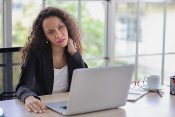 Mid adult businesswoman touching her neck on table in office after bad news business failure or get...