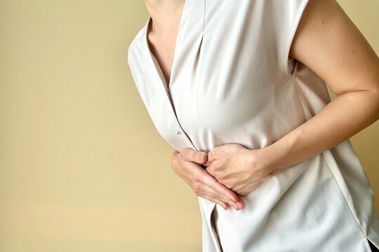胃の部分をおさえる女性のイメージ