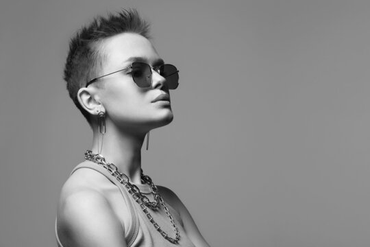 Young beautiful woman with short hair and a chain necklace in glasses